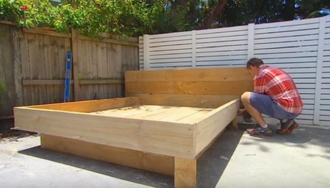رجل يبني السرير في منتصف الفناء.