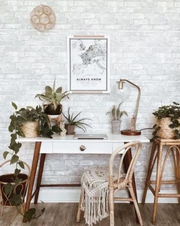 مكتب منزلي أنيق بوهو مع طاولة خشبية ريترو ، سجادة بوهو ، حرفة جدارية ، الكثير من النباتات المنزلية: الصبار والعصارة